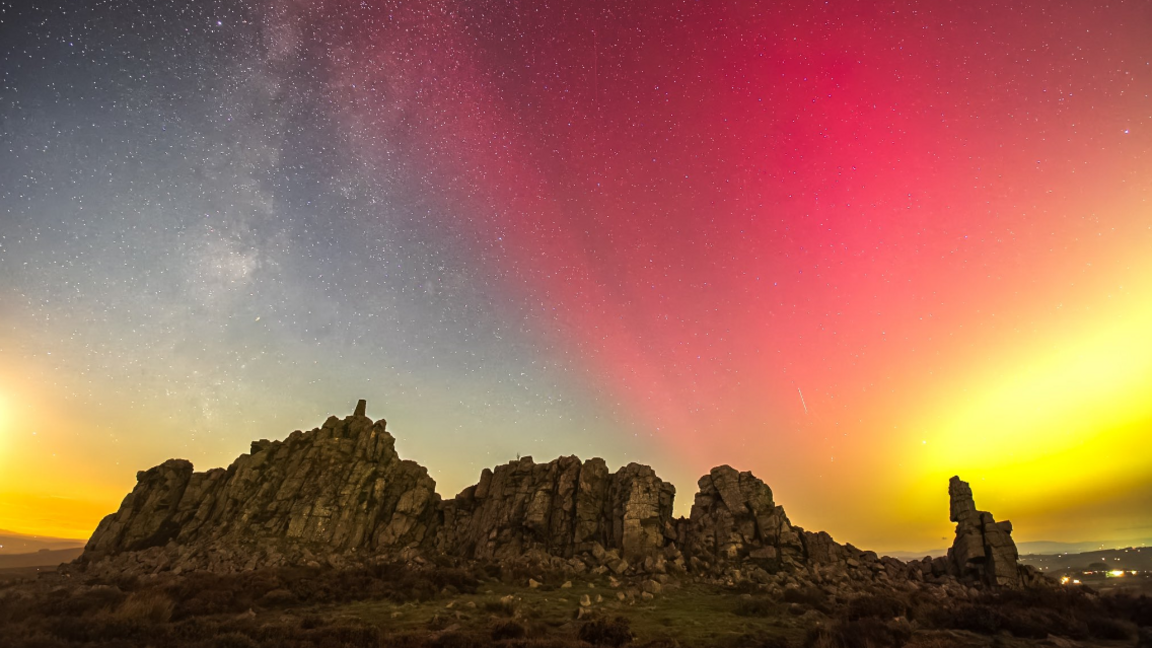 Northern Lights over the Stiperstones in Shropshire. Sheets of red and yellow appear in the sky over a rocky hilltop crag on an otherwise clear night