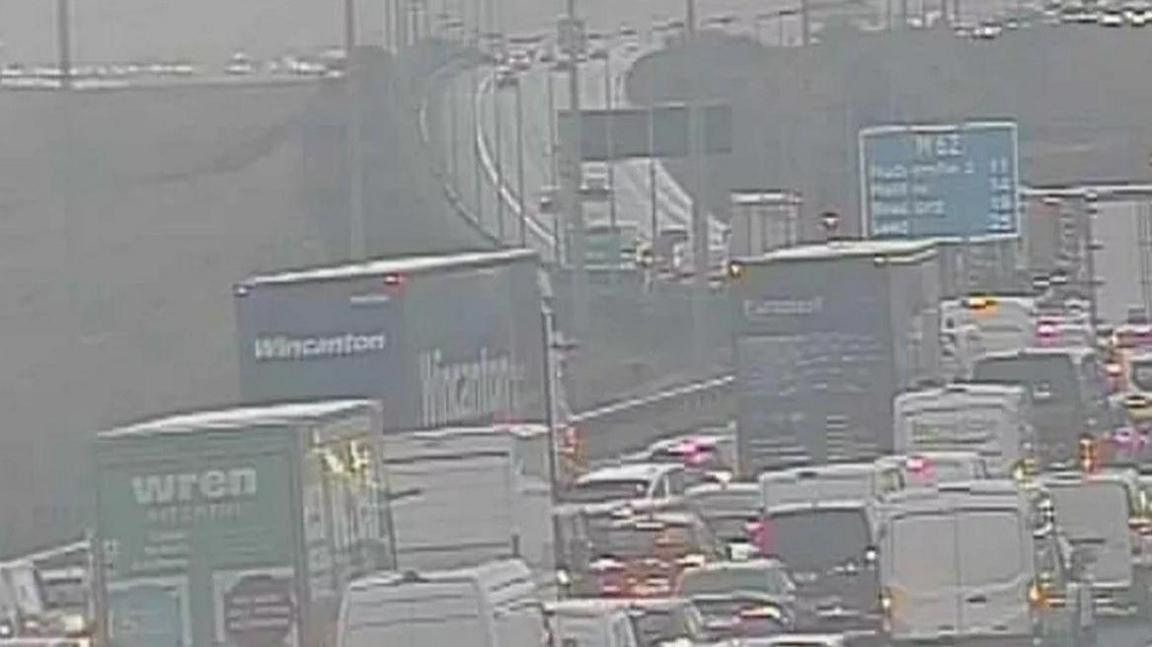 Congestion on M62 with lots of lorries, vans and cars seen amid much spray on a very wet morning