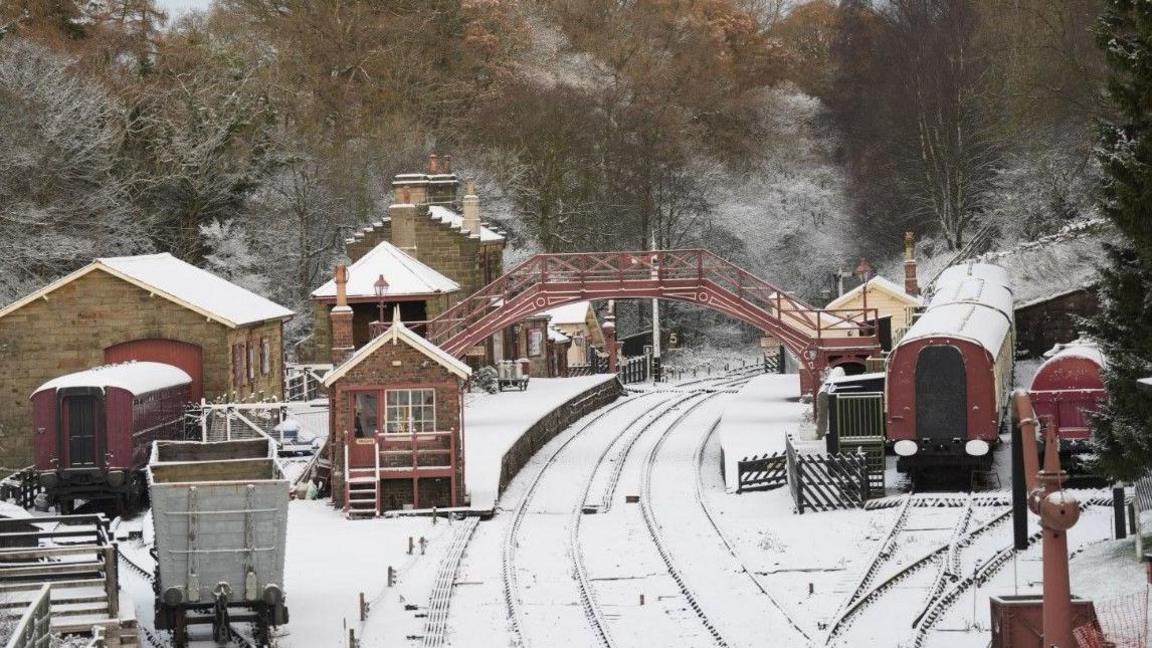 Snow-covered rail tracks and platforms at Goathland Station on the North Yorkshire Moors Railway.