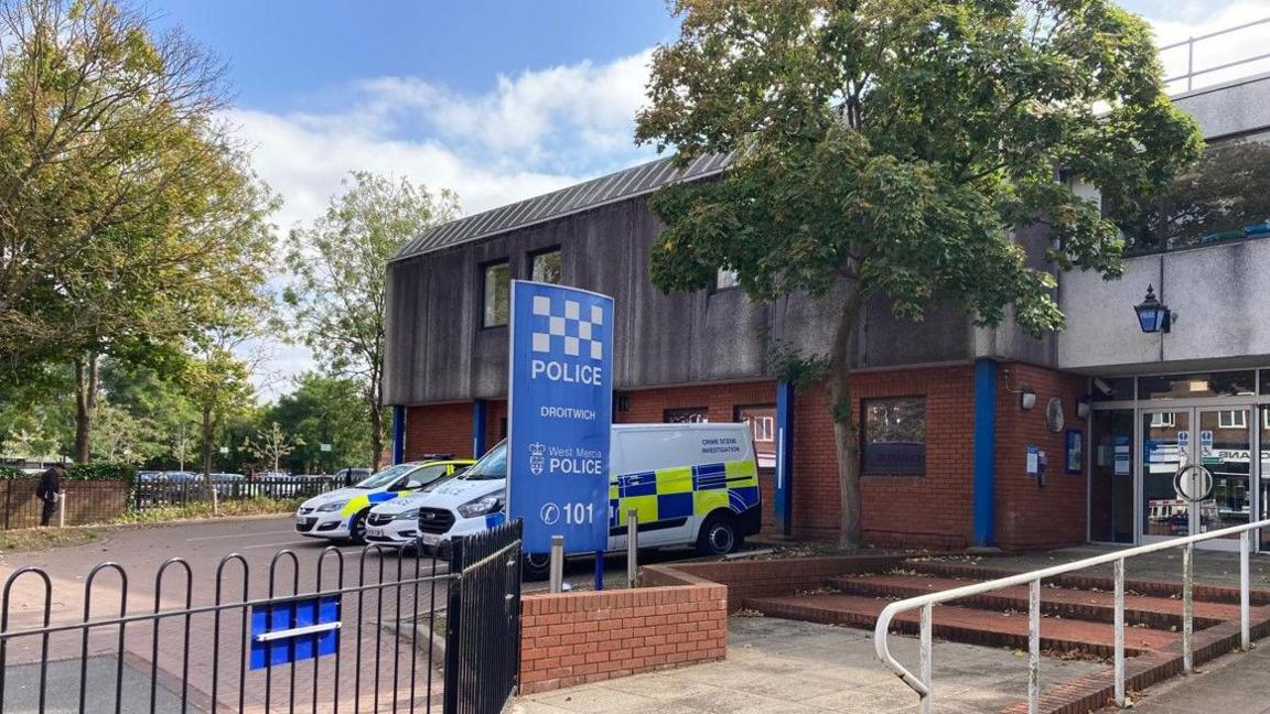 Droitwich police station, with vehicles parked outside near a sign