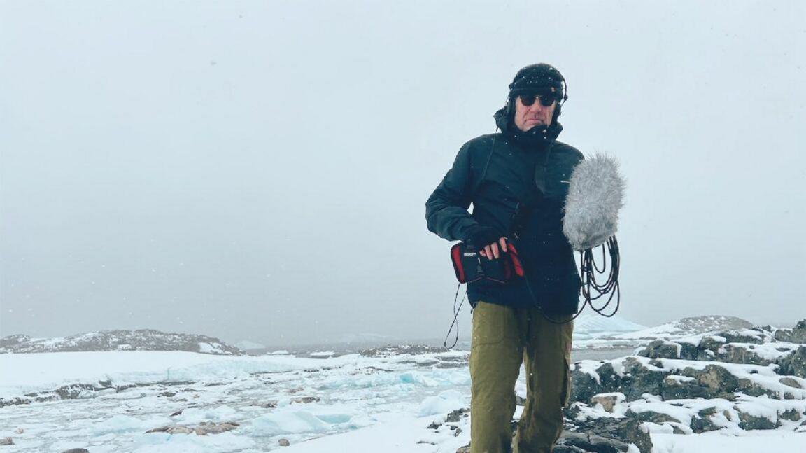 Michael Begg standing in Antarctica while recording and filming 