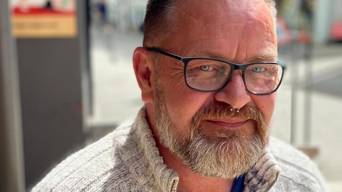 Close-up portrait of Rob Smale with glasses, a short beard and a nose piercing