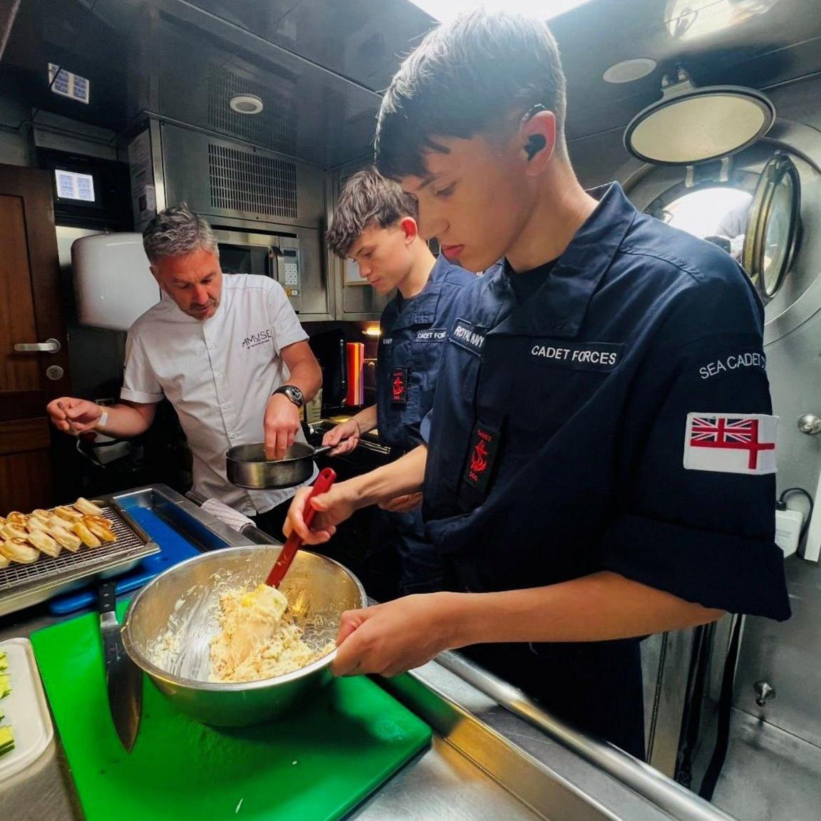 Tall Ships cadets with a chef inside one of the boats, preparing food.