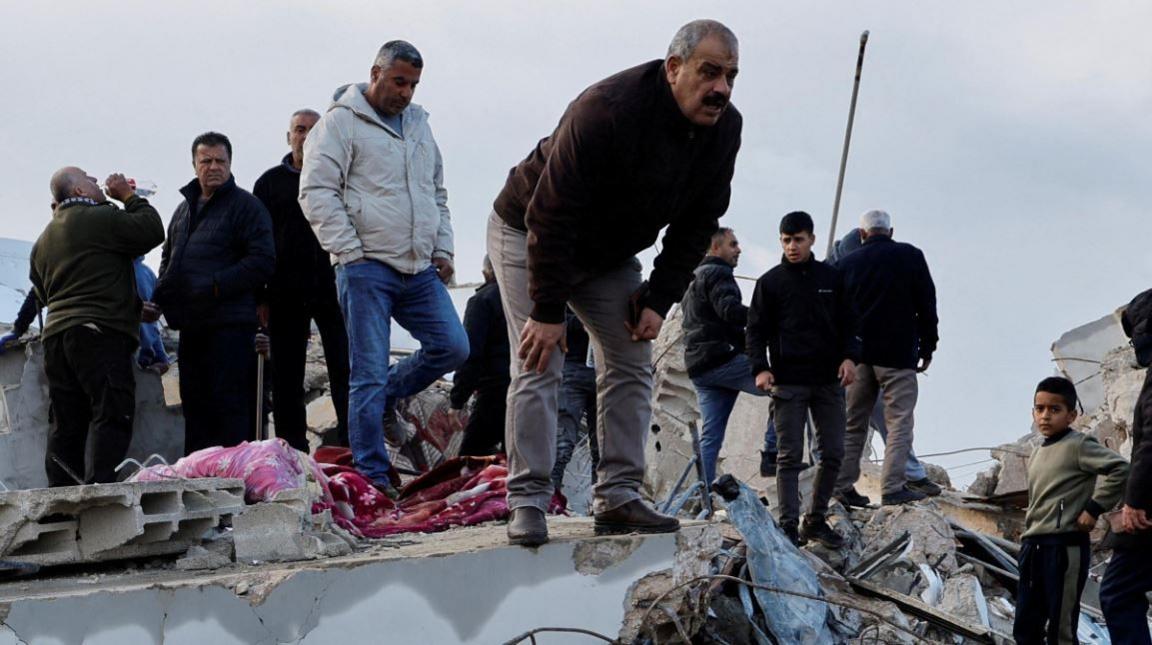 Palestinians stand on remains of demolished building in Burqin (23/01/25)