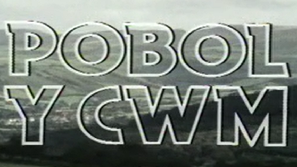 Teitlau gwreiddiol Pobol y Cwm. Y geiriau mewn llythrennau mawr rhimyn gwyn gyda chwm a mynyddoedd gwyrdd yn y cefndir