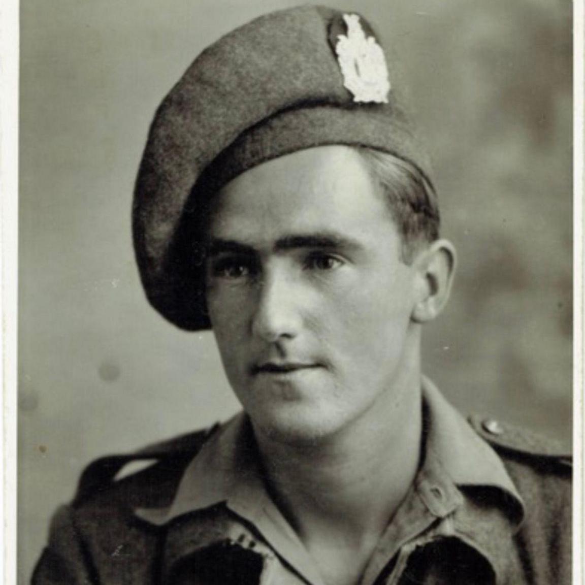 A old black and white polaroid photo taken of a young solider in his army uniform.