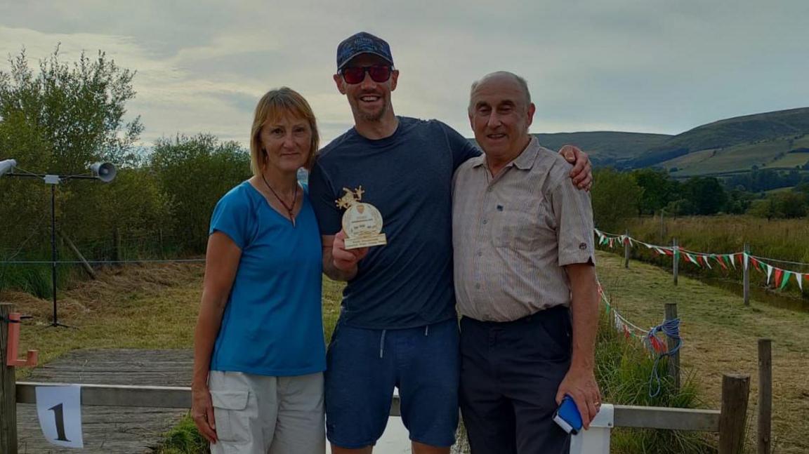 Rutter (centre) stands in between his mother (left) and his father (right). 