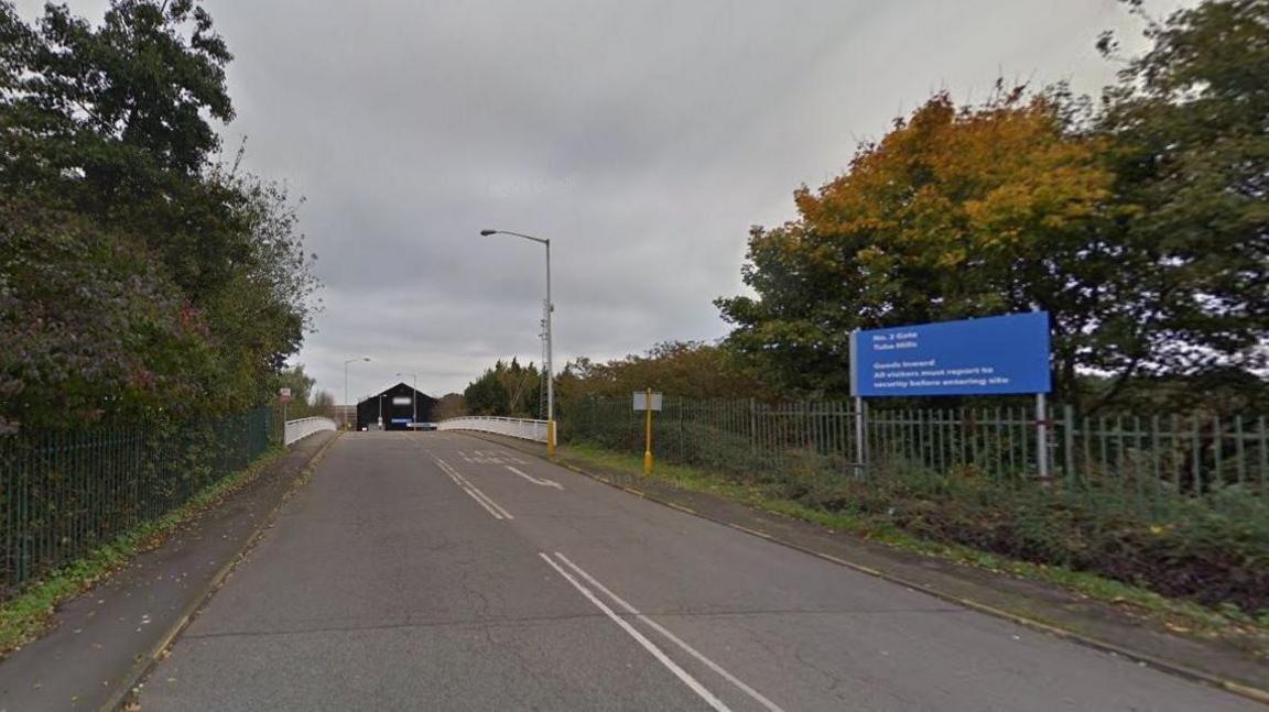 Entrance to factory site, showing sign and gates