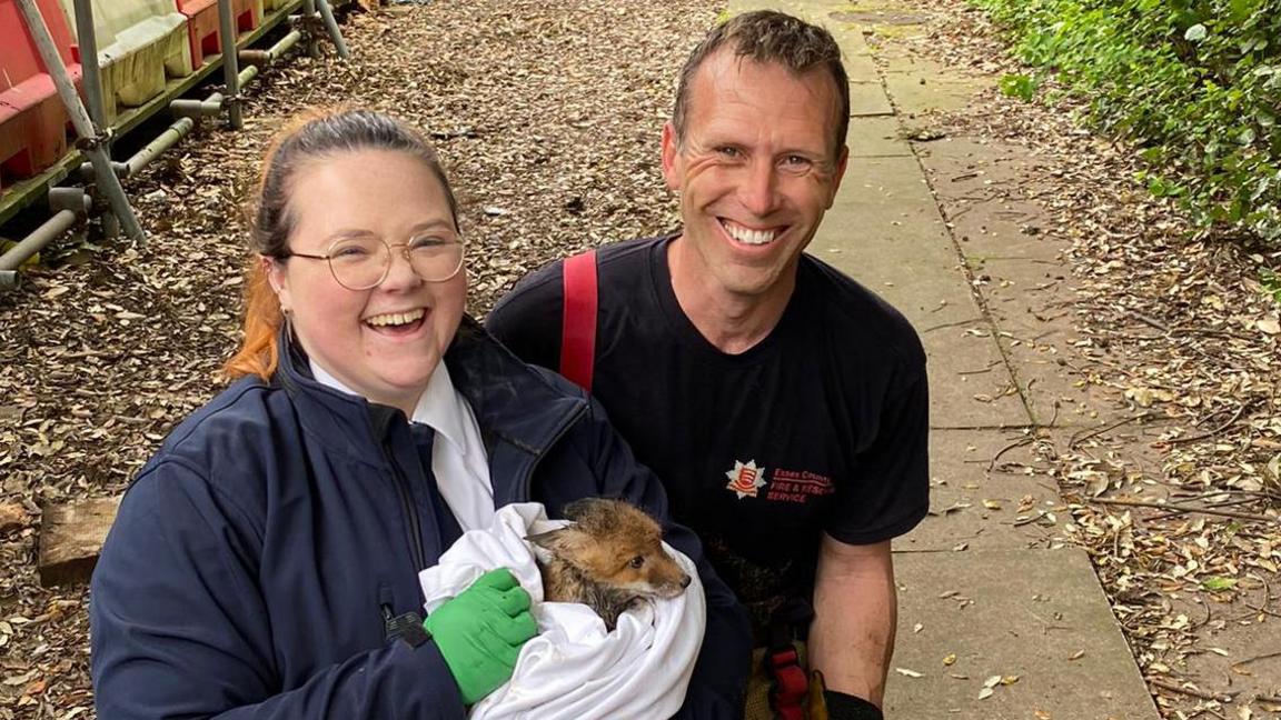 Two people holding a rescued fox