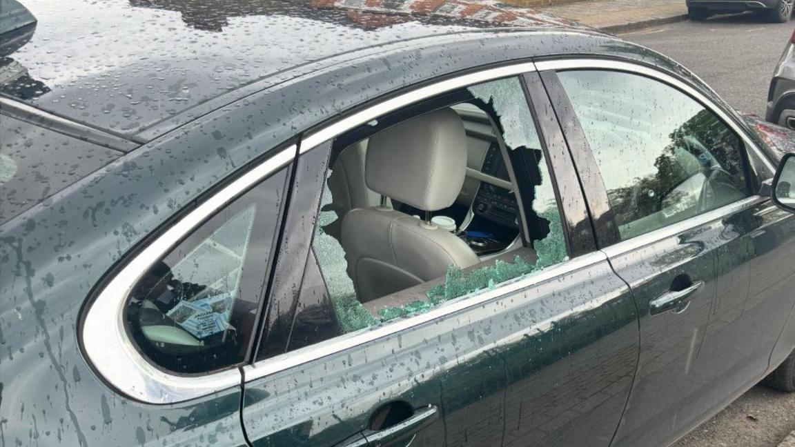 A smashed rear right-hand window on a bottle green car.