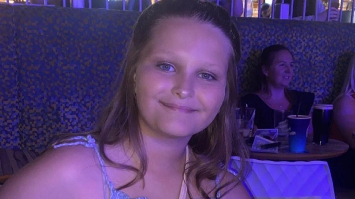 A handout of Mia Lucas smiling with her hair tied back wearing a summery top