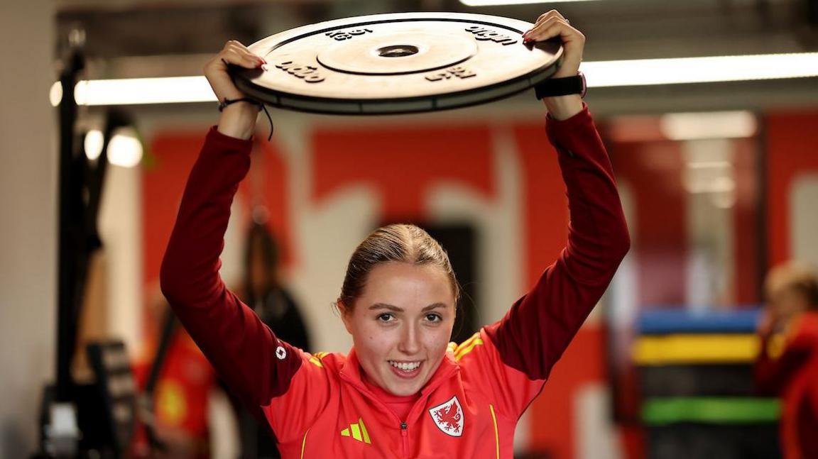 Mared Griffiths lifts a weight above her head in the gym 