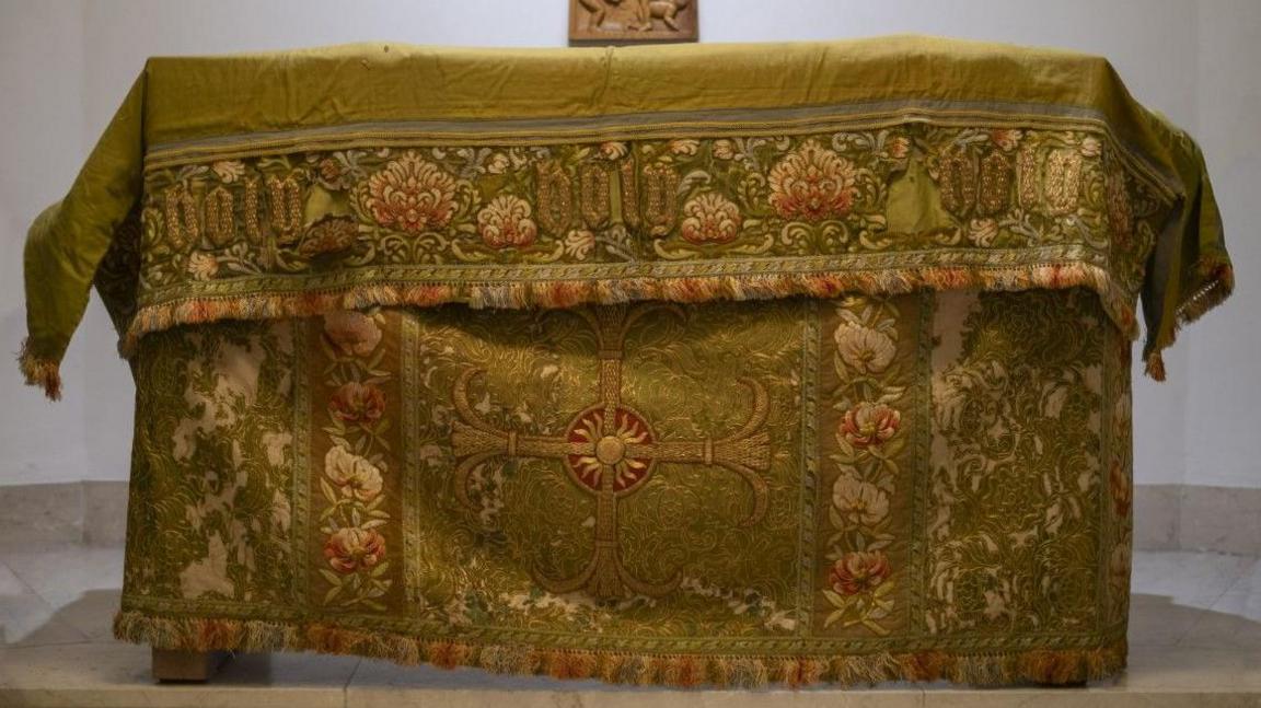 A green and red embroidered altar front with a cross at Bradford Cathedral
