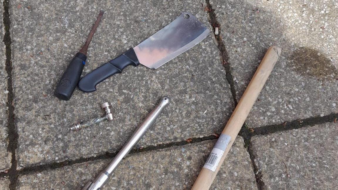 Meat cleaver, chisel and other objects used as weapons laid on the pavementwscre