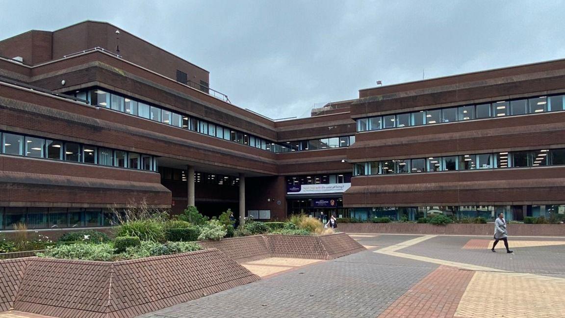 A general view of the Wolverhampton civic centre showing a bricked paved  surface in front of an ageing brown brick L-shaped building