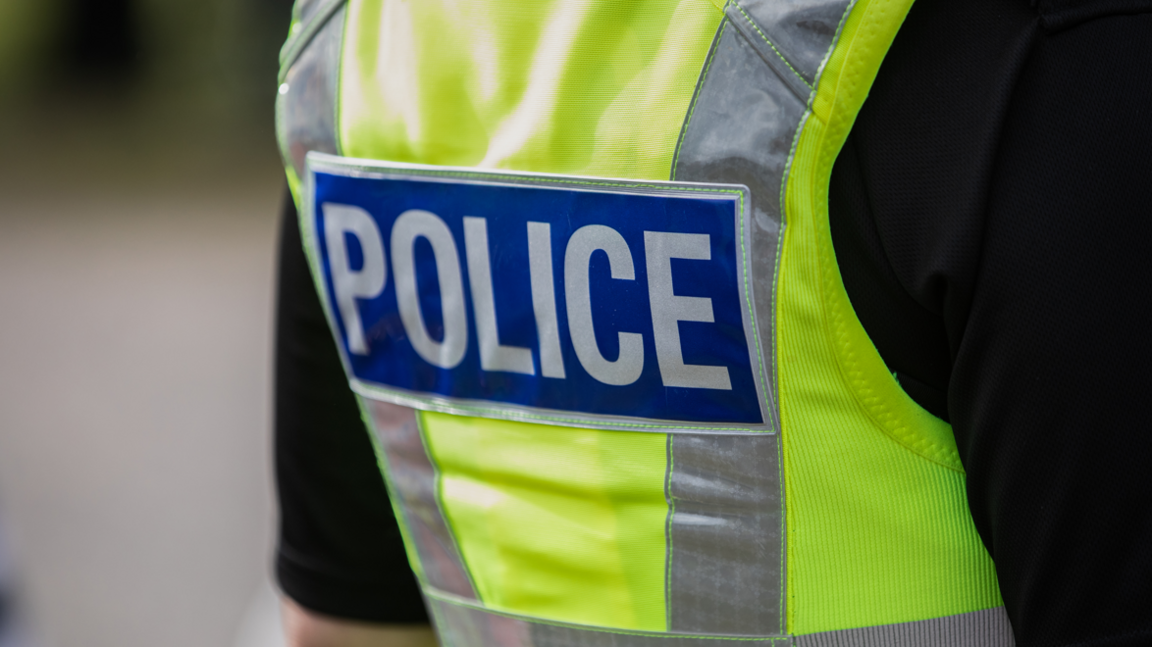 Back of a police officer's uniform, showing a fluorescent vest saying 'police'