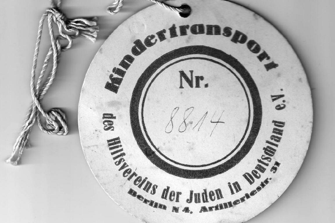 Close up of a circular Kindertransport tag, designed to be tied to luggage or clothing with string