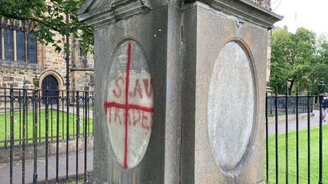Gravestone in Lancaster Priory vandalised with the words slave trader and a red cross.
