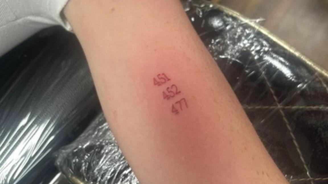 Saffron Dixon's arm, with a tattoo, which has three numbers in red ink on 451, 452 and 477 