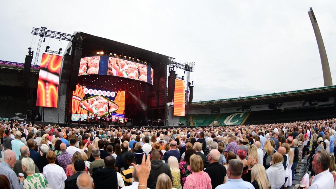 Rod Stewart on stage in Northampton with crowds of people watching.