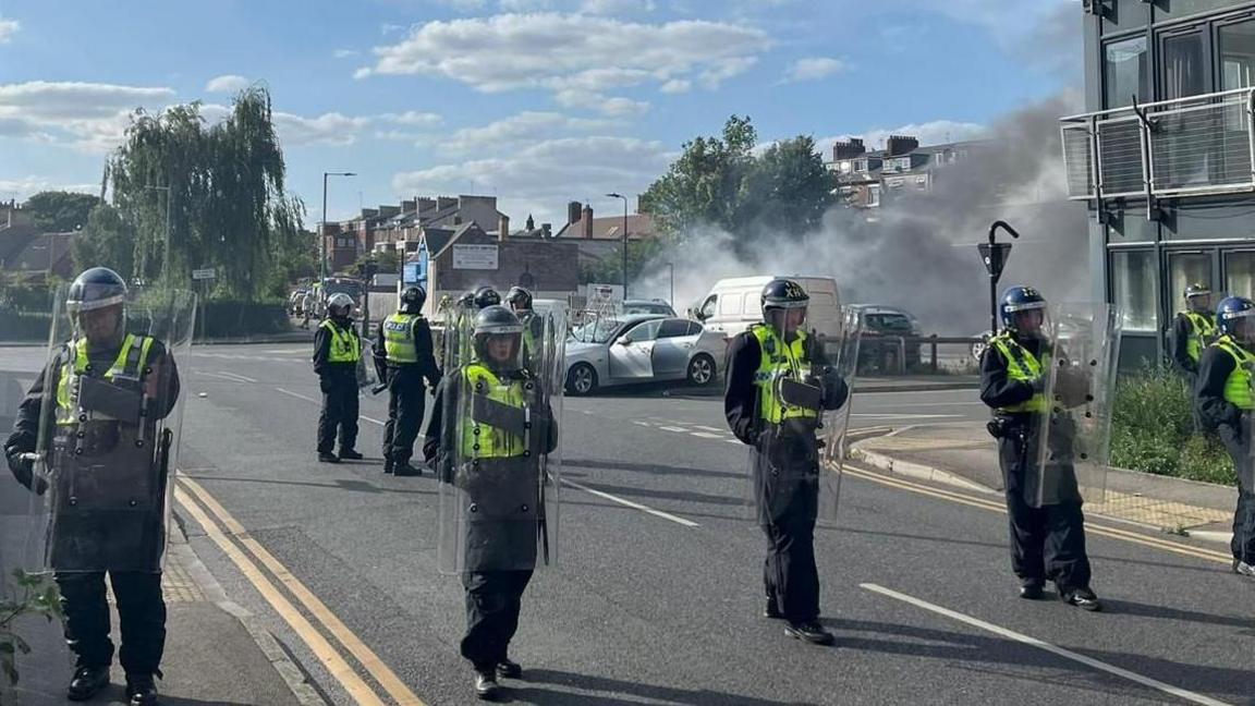 Police officers in a line across a residential road with the silver BMW in the background