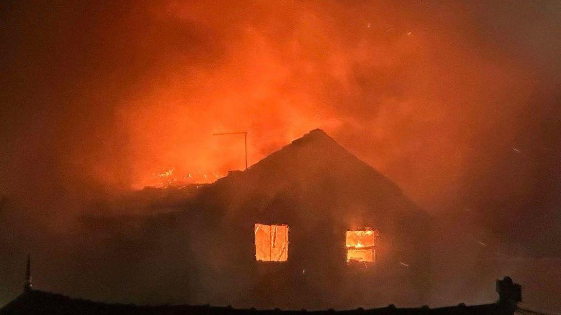 Huge fire at a derelict hotel in Blackpool. Bright orange flames have engulfed the building, which is viewable only in silhouette with its windows shot out.