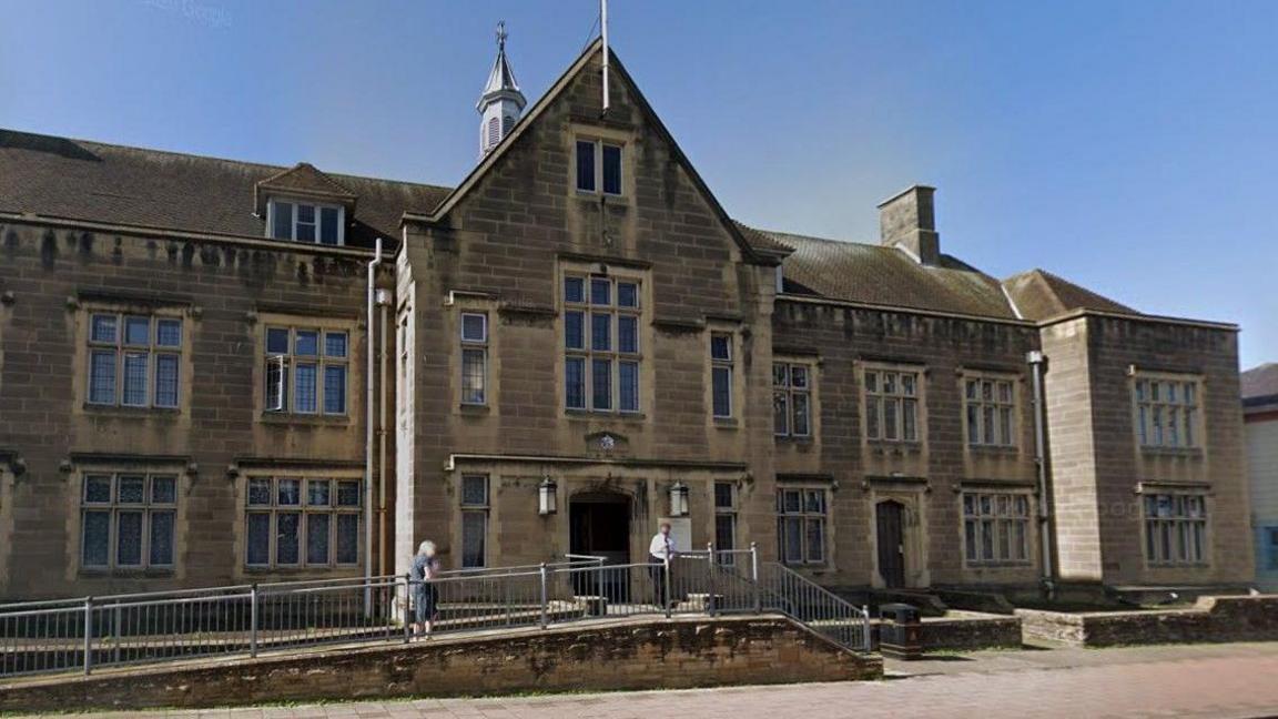 The exterior of Carlisle Magistrates' Court. It is a two-storey yellow brick building.