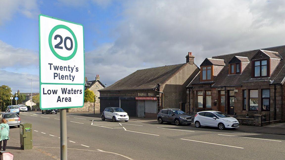 road sign and street with houses behind