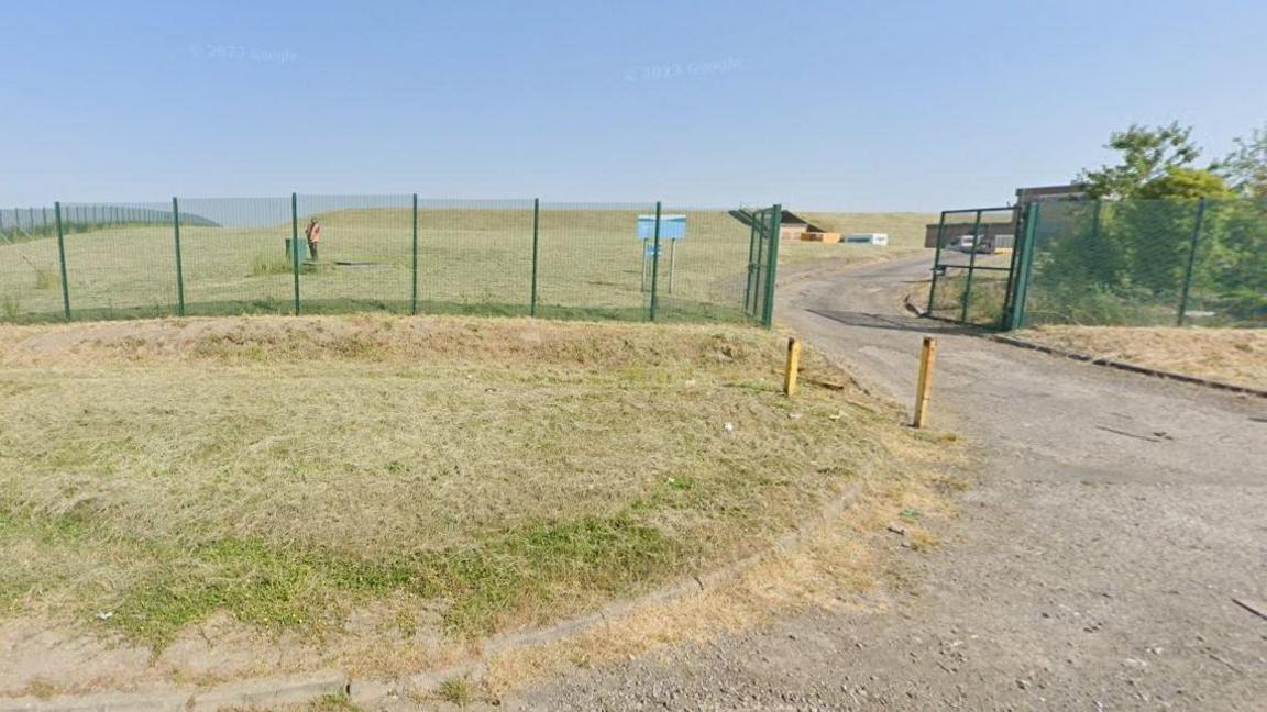 A grassy area surrounded by a black, wire-mesh fence