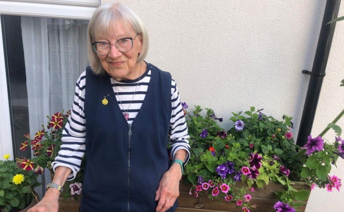 Happy in blue and white wearing glasses outside near flowers