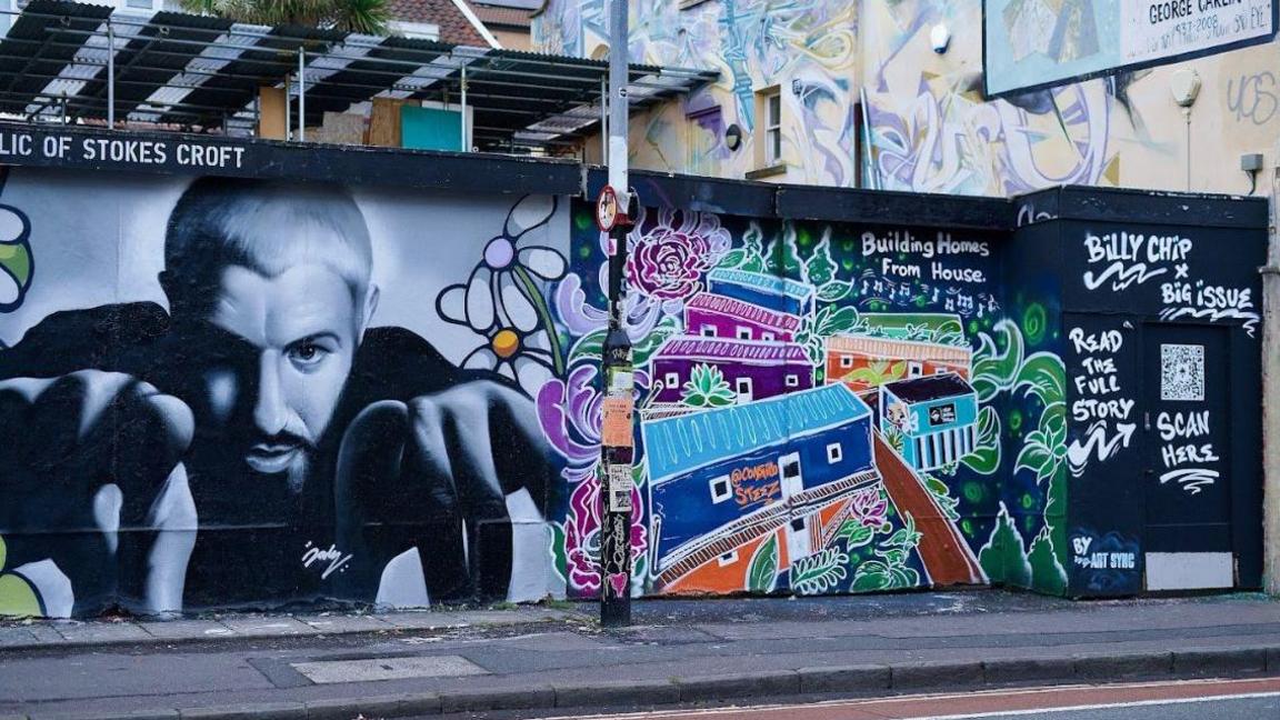 Two sections of the mural side by side - one showing the man in black and white pointing out to members of the public on the left, on the right the Help Bristol's Homeless microhomes on the right. The QR code where people can find more about the fundraiser can be seen on the left of the microhomes section.