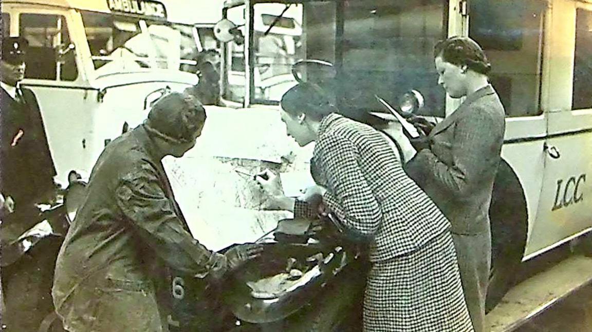 Two women looking into the engine of an ambulance 