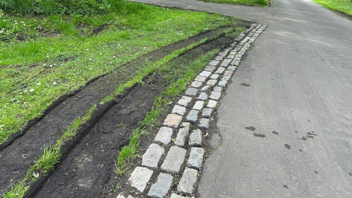 Muddy tyre tracks across grass in the park