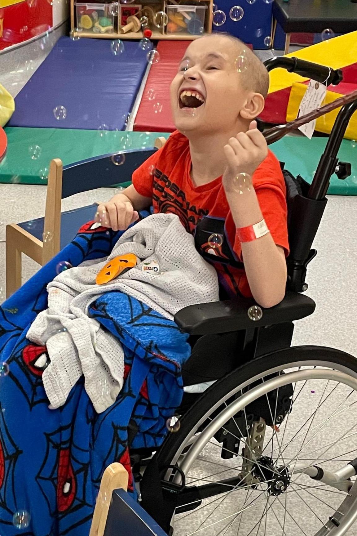 Ben in a wheelchair looking happy with bubbles in the air