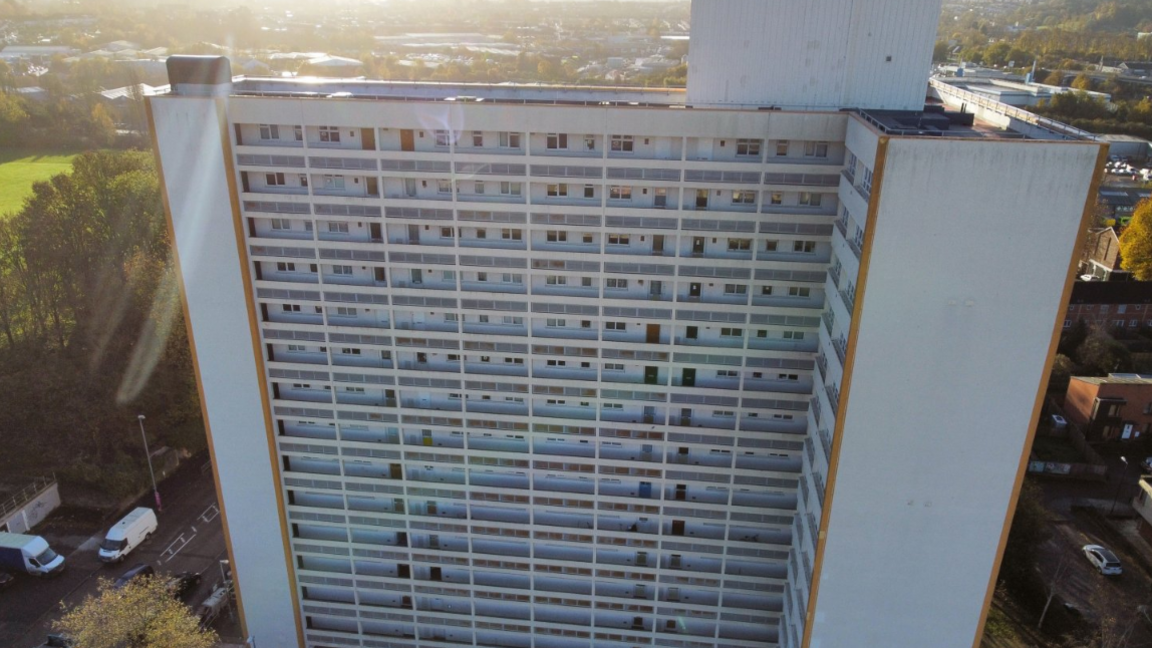 A file image of Barton House in Bristol - a high-rise white, blue and yellow building in an 'l' shape - with sunrays appearing behind it