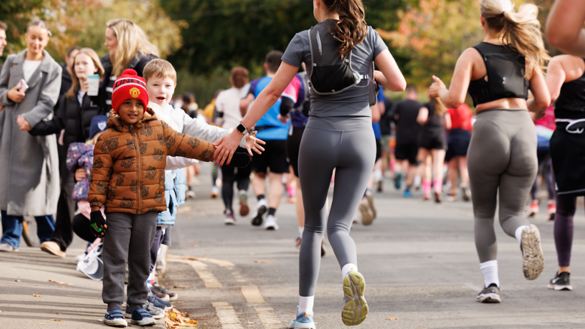 A young child stands on the pavement and gives a high five to a runner going past him at last year's event