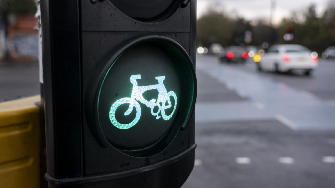 An illuminated cycle lane sign with cars in the background