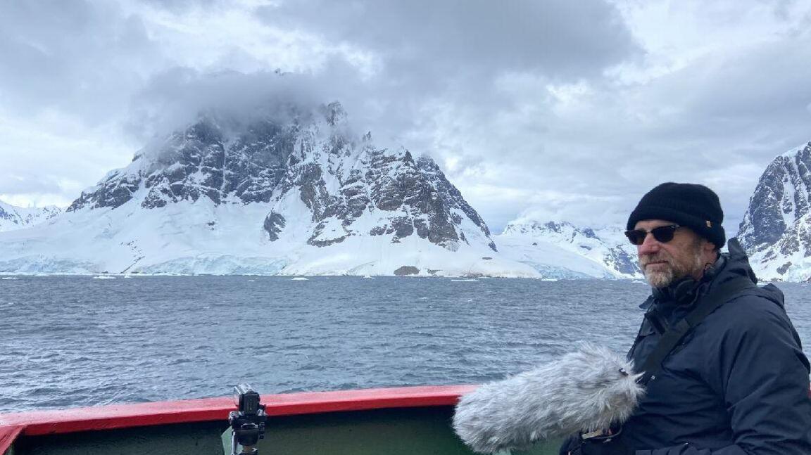 Michael Begg standing in Antarctica while recording and filming 