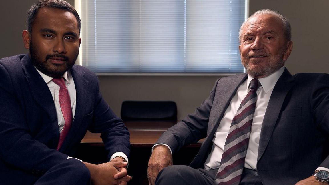 Amol Rajan and Lord Sugar, sat down and wearing suits, looking into the camera