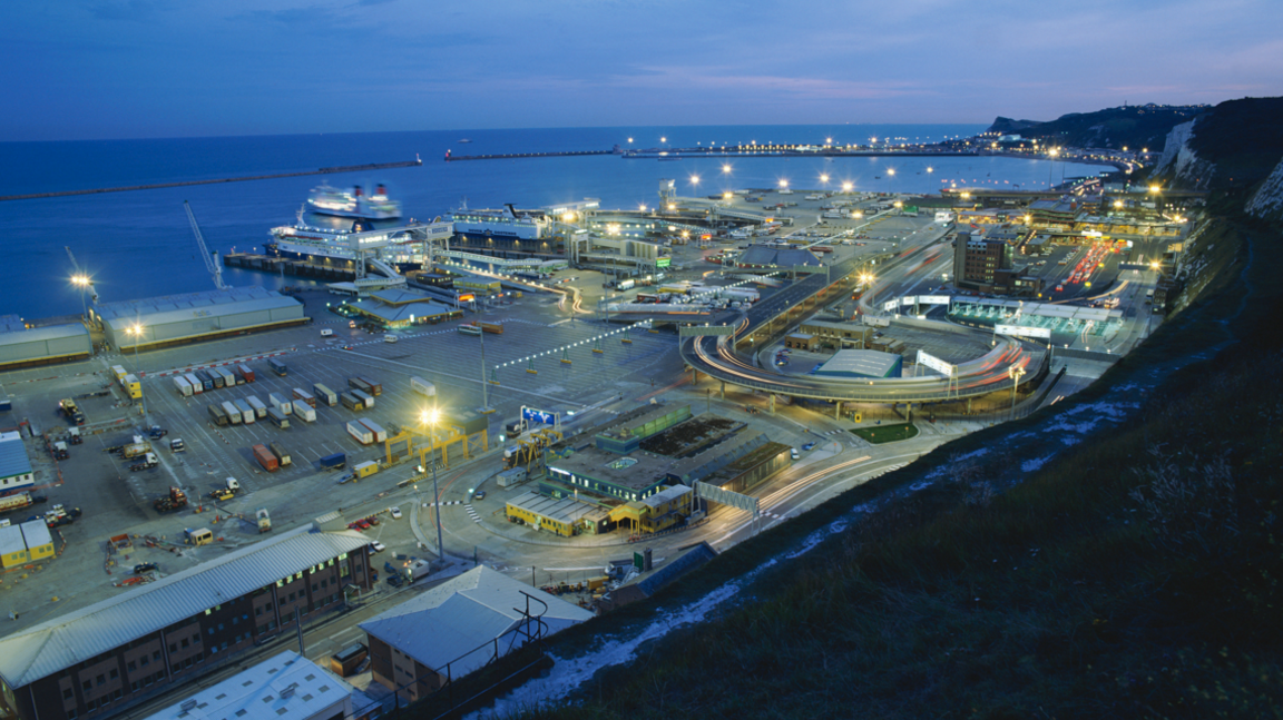 A view of the port of Dover at dusk from the White Cliffs above the port, showing ferries and traffic.