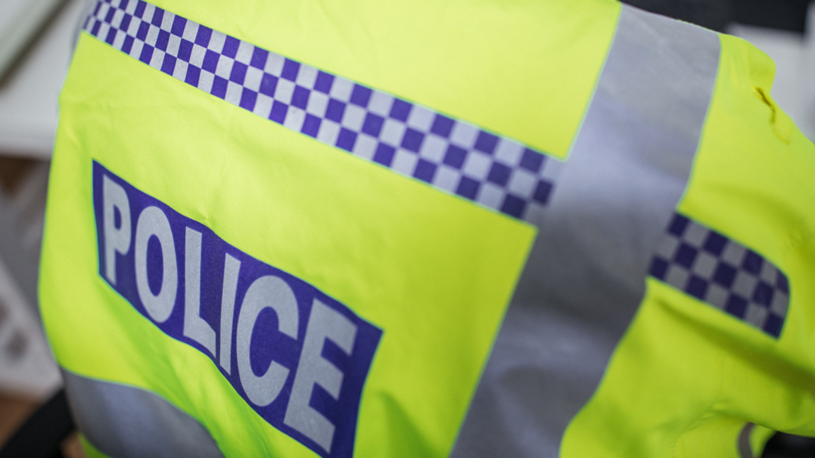 The back of a police officers hi-vis vest with the word police written on