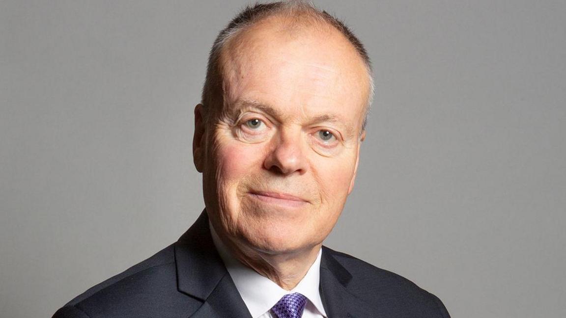 Official parliamentary portrait photo of Clive Betts. He has short grey hair and is wearing a black suit jacket, white shirt and purple tie.