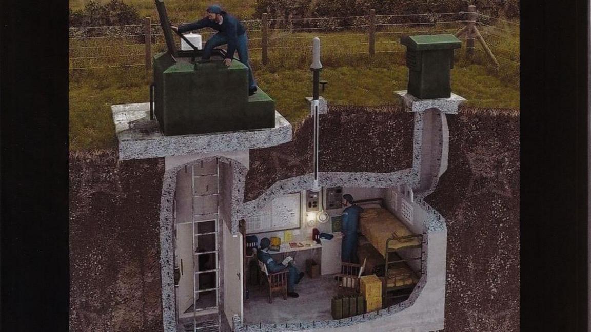 Artists impression of living conditions within the nuclear bunker showing one man climbing in through the access hatch, on the top left, with the ladder shown beneath, and a man sitting at a desk with another man standing near a bunk bed on the right, with the ventilation shaft to the surface