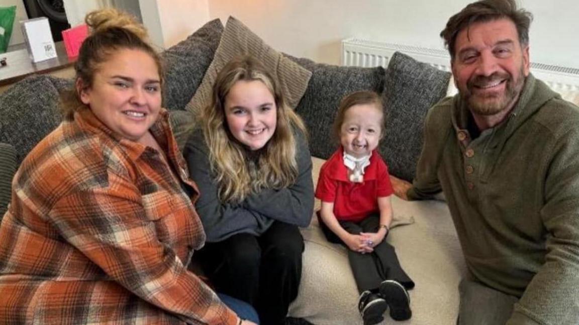 The show's presenter, Nick Knowles, told the family the news that would change their lives. He is sat on a sofa with Isla and her family.