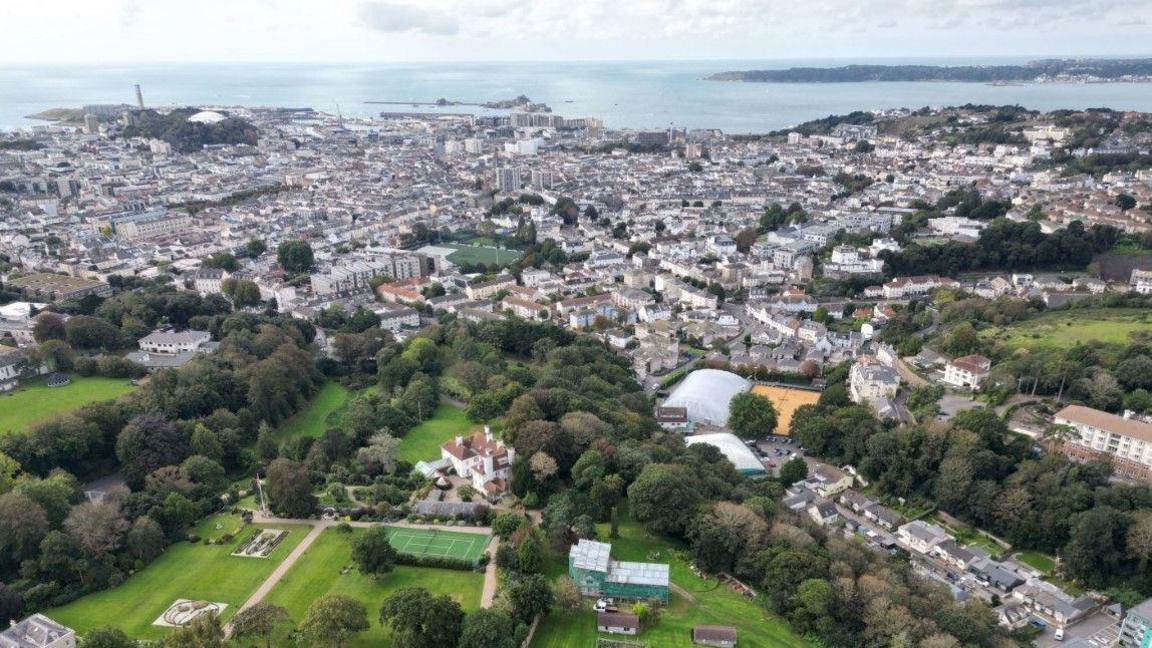 Aerial image of St Helier in Jersey shows buildings and green spaces. The sea can be seen in the distance.