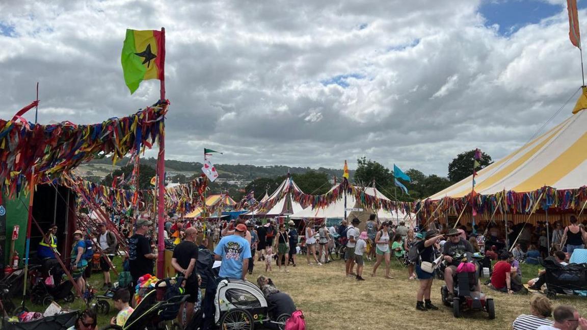 A selection of large white marquee tents with bunting linking them along with crowds of families.