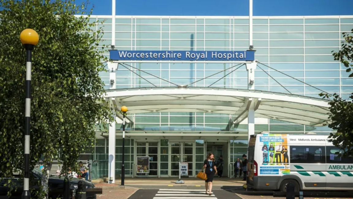 Worcestershire Royal Hospital, a glass fronted building with a blue sign and an ambulance parked in front