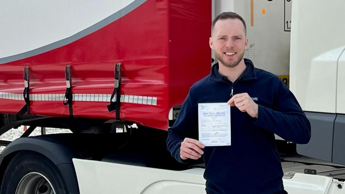 David Boutflour holds a certificate showing his HGV qualification