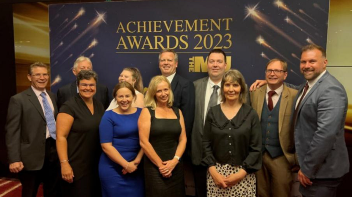11 people part of the Homes & Horizons project after winning an MJ award. All smiling looking at the camera