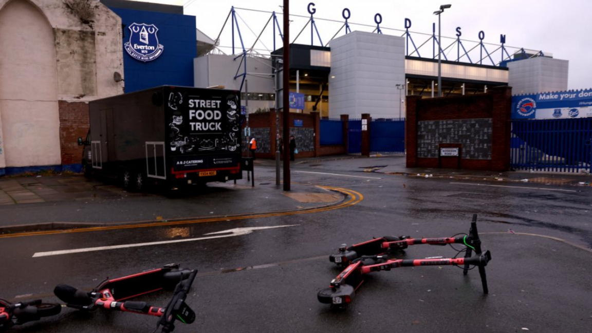 Two electric scooters blown over in the wind outside an empty Goodison Park